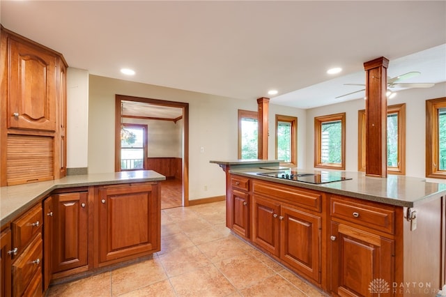 4911 Arabian Dr, Fairborn, OH 45324 - kitchen with ornate columns, black electric stovetop, healthy amount of natural light, and brown cabinetry