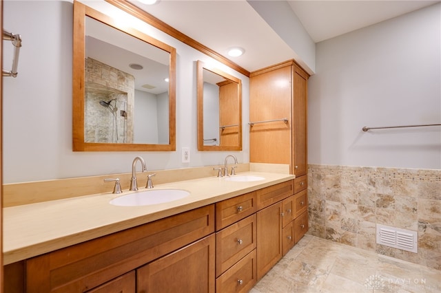 4911 Arabian Dr, Fairborn, OH 45324 - bathroom featuring double vanity, a tile shower, a wainscoted wall, and tile walls