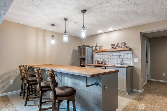 8695 Dijon Ct, Washington Twp, OH 45458 - kitchen with butcher block countertops, a kitchen bar, a peninsula, a textured ceiling, and pendant lighting