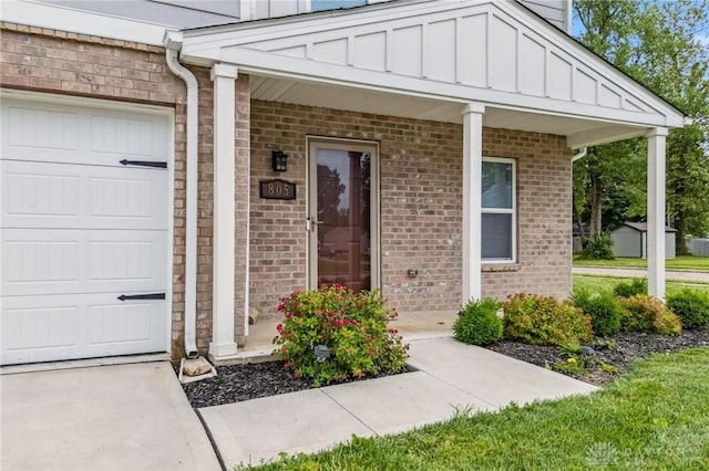 805 Marshall Dr, Xenia, OH 45385 - view of exterior entry with covered porch, a garage, board and batten siding, and brick siding