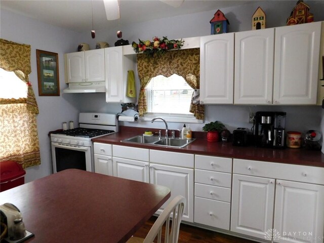 316 Center St, Lebanon, OH 45036 - kitchen featuring white range with gas stovetop, under cabinet range hood, dark countertops, and white cabinetry