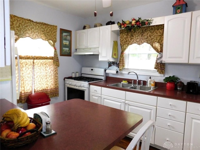 316 Center St, Lebanon, OH 45036 - kitchen featuring white gas stove, under cabinet range hood, dark countertops, and white cabinets