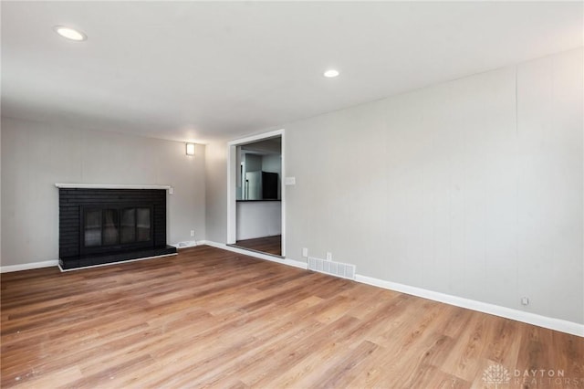 610 N Spring St, Wilmington, OH 45177 - unfurnished living room featuring wood finished floors, a brick fireplace, and recessed lighting