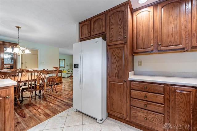 9131 Shawhan Dr, Centerville, OH 45458 - kitchen featuring white refrigerator with ice dispenser, light countertops, brown cabinets, and hanging light fixtures