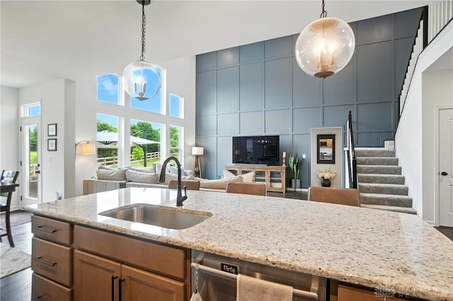 4835 Granada Ct, Liberty Twp, OH 45044 - kitchen featuring stainless steel dishwasher, open floor plan, light stone counters, pendant lighting, and brown cabinets