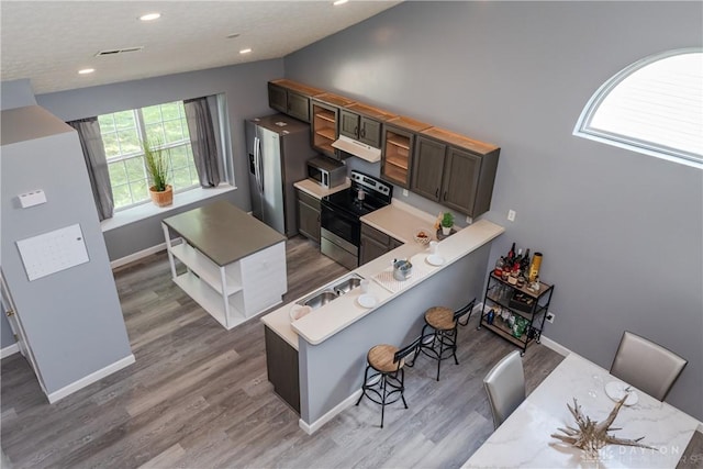 160 Worthington Dr, Germantown, OH 45327 - kitchen featuring appliances with stainless steel finishes, a kitchen breakfast bar, light countertops, light wood finished floors, and under cabinet range hood