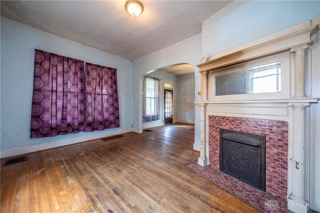 246 N D St, Hamilton, OH 45013 - unfurnished living room with arched walkways, wood-type flooring, a tiled fireplace, and healthy amount of natural light