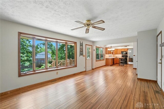 356 Saint James Pl, Springboro, OH 45066 - unfurnished living room featuring a chandelier, a ceiling fan, a textured ceiling, and light wood-type flooring