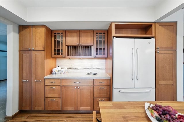 356 Saint James Pl, Springboro, OH 45066 - kitchen featuring freestanding refrigerator, brown cabinets, wood finished floors, glass insert cabinets, and decorative backsplash