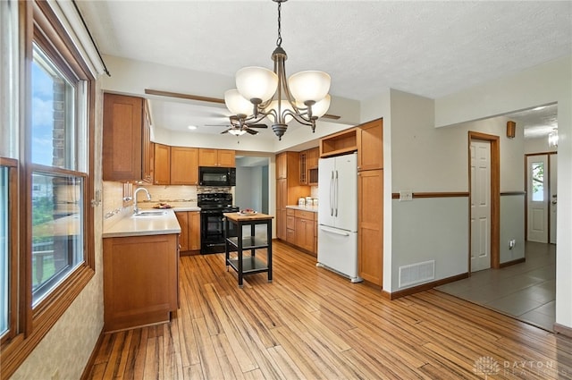 356 Saint James Pl, Springboro, OH 45066 - kitchen with black appliances, light wood-style floors, a chandelier, light countertops, and brown cabinetry