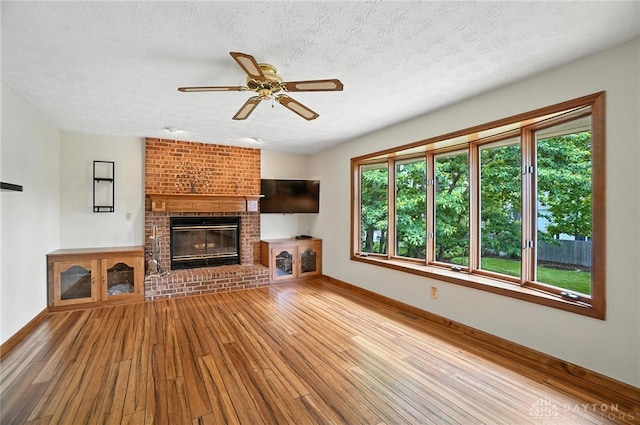 356 Saint James Pl, Springboro, OH 45066 - unfurnished living room featuring ceiling fan, hardwood / wood-style flooring, healthy amount of natural light, a textured ceiling, and a brick fireplace