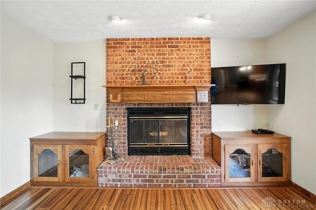 356 Saint James Pl, Springboro, OH 45066 - unfurnished living room featuring wood finished floors, a brick fireplace, and a textured ceiling