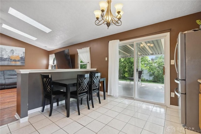 5545 Stone Path Dr, Middletown, OH 45042 - dining room featuring a chandelier, a textured ceiling, a skylight, lofted ceiling, and light tile patterned floors