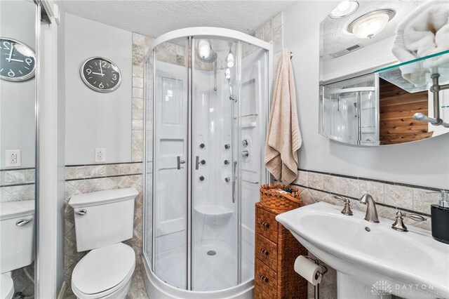 255 Belle Watlin Ct, Dayton, OH 45434 - bathroom featuring tile walls, a wainscoted wall, a shower stall, and a textured ceiling