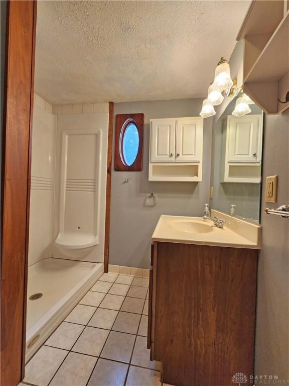 3054 Carpenter Rd, Jefferson Twp, OH 45335 - bathroom featuring a textured ceiling, vanity, tile patterned flooring, and a shower