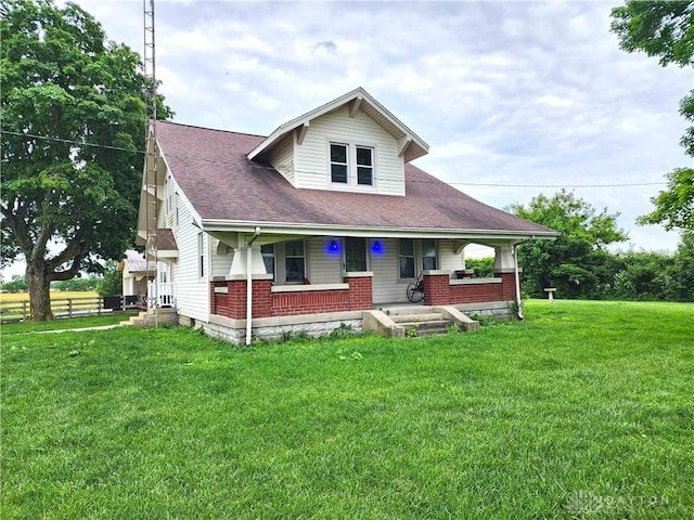 3054 Carpenter Rd, Jefferson Twp, OH 45335 - bungalow featuring a front lawn, covered porch, brick siding, and a shingled roof