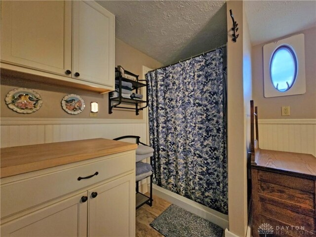 3054 Carpenter Rd, Jefferson Twp, OH 45335 - bathroom with a textured ceiling, a wainscoted wall, a shower with curtain, and vanity