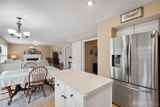 25 Huntley Ct, Springboro, OH 45066 - kitchen featuring stainless steel fridge with ice dispenser, a chandelier, light wood finished floors, a fireplace, and white cabinets