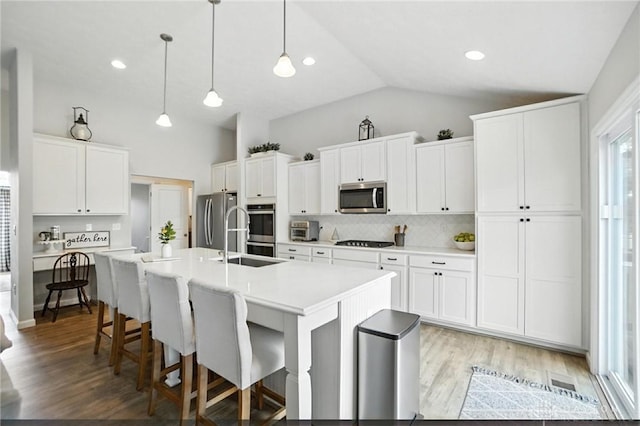 3109 Running Deer Trl, Franklin Twp, OH 45005 - kitchen featuring appliances with stainless steel finishes, backsplash, a breakfast bar area, a center island with sink, and light countertops