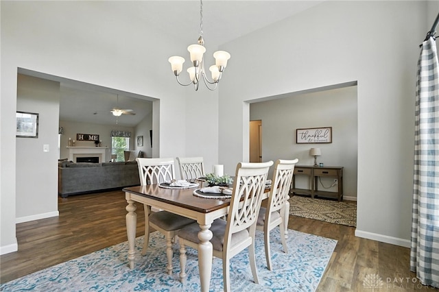 3109 Running Deer Trl, Franklin Twp, OH 45005 - dining area featuring wood finished floors, a chandelier, a fireplace, a ceiling fan, and a high ceiling