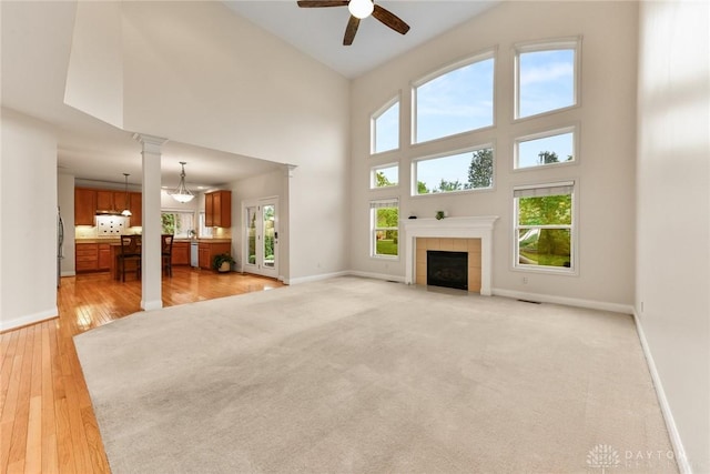 9764 Olde Georgetown Way, Dayton, OH 45458 - unfurnished living room with ceiling fan, a high ceiling, a tiled fireplace, and light wood finished floors