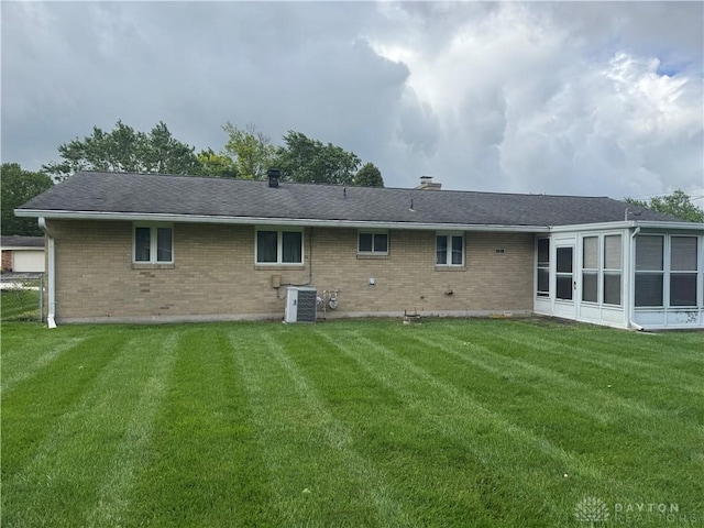 435 Nies Ave, Englewood, OH 45322 - rear view of house with brick siding, a lawn, a chimney, and a sunroom