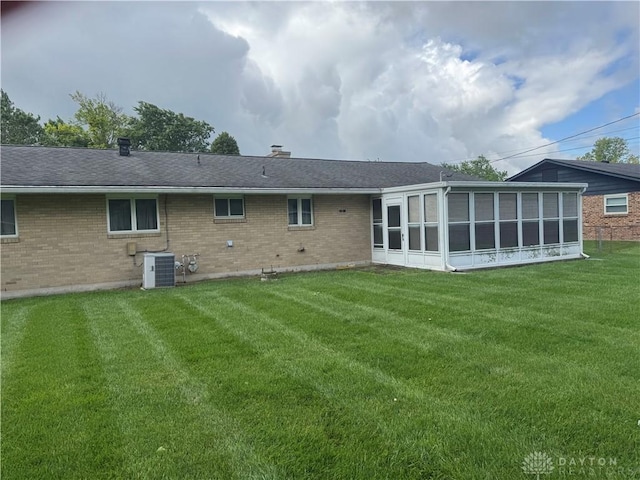 435 Nies Ave, Englewood, OH 45322 - back of property with brick siding, a sunroom, a lawn, and a chimney