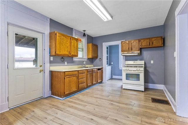 119 Wilson St, Hamilton, OH 45011 - kitchen with gas range gas stove, under cabinet range hood, brown cabinets, and light countertops
