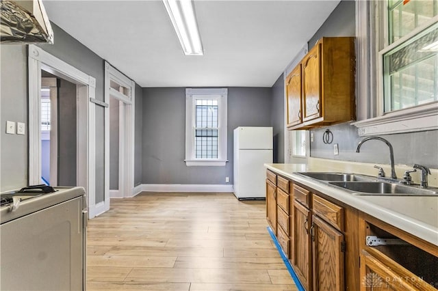 119 Wilson St, Hamilton, OH 45011 - kitchen with freestanding refrigerator, brown cabinets, light wood-style flooring, and light countertops