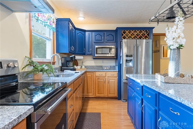 2610 Yorktown Ct, Beavercreek, OH 45434 - kitchen with stainless steel appliances, range hood, light wood-type flooring, blue cabinets, and light stone counters