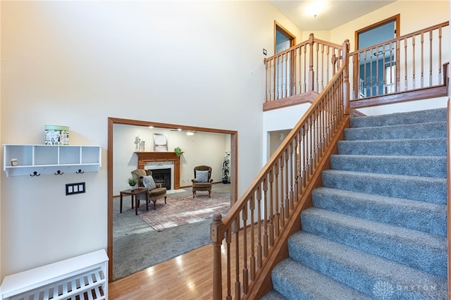 2610 Yorktown Ct, Beavercreek, OH 45434 - staircase featuring wood finished floors, a glass covered fireplace, and a high ceiling