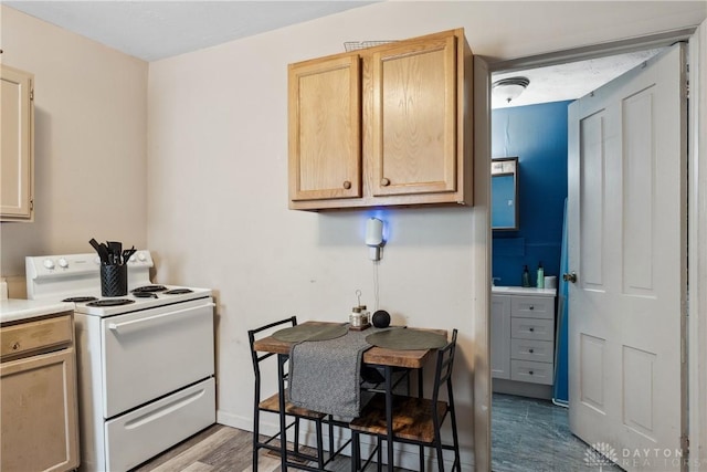 711 E 2nd St, Xenia, OH 45385 - kitchen with white range with electric cooktop, wood finished floors, light countertops, and light brown cabinets