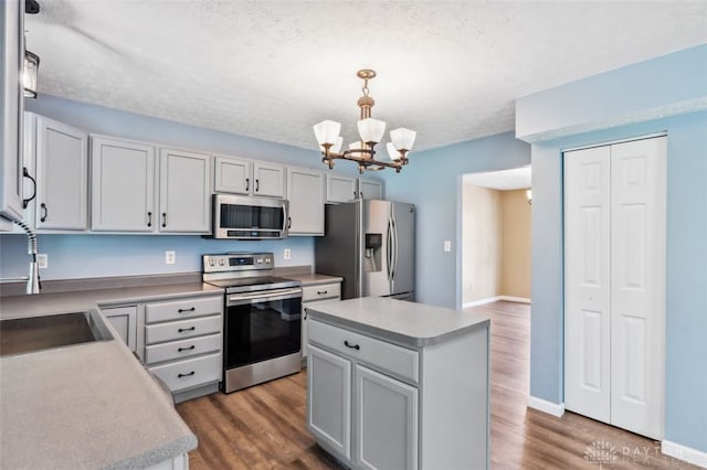 110 Easton Manor Dr, Monroe, OH 45050 - kitchen featuring appliances with stainless steel finishes, a chandelier, wood finished floors, a center island, and a textured ceiling