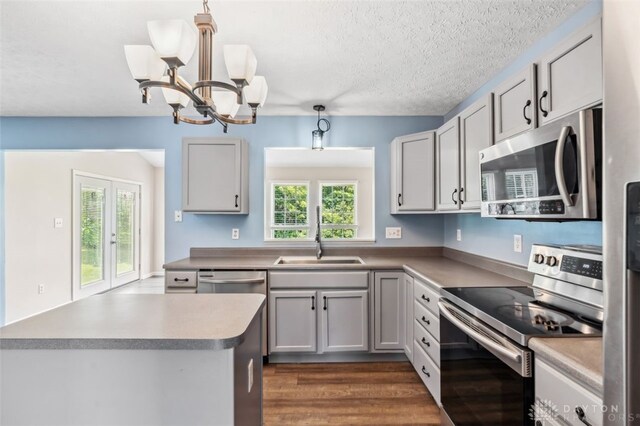 110 Easton Manor Dr, Monroe, OH 45050 - kitchen featuring stainless steel appliances, a chandelier, hanging light fixtures, dark wood-type flooring, and a textured ceiling