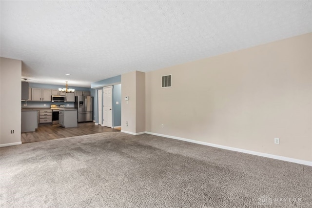 110 Easton Manor Dr, Monroe, OH 45050 - unfurnished living room featuring a chandelier, carpet flooring, and a textured ceiling