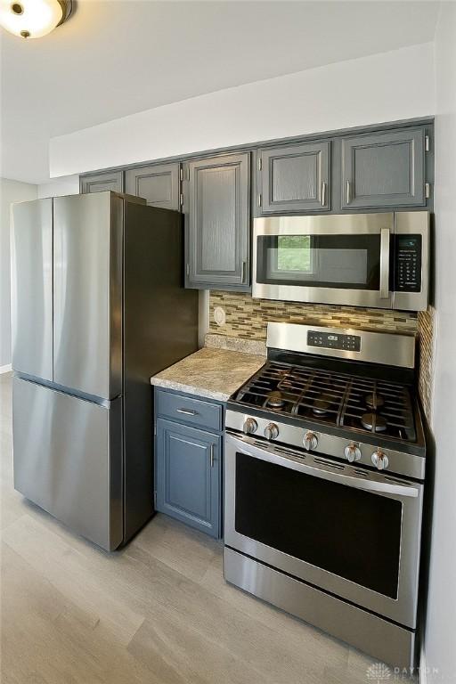 400 S Hayden Ave, Riverside, OH 45431 - kitchen featuring appliances with stainless steel finishes, gray cabinets, light wood finished floors, and backsplash