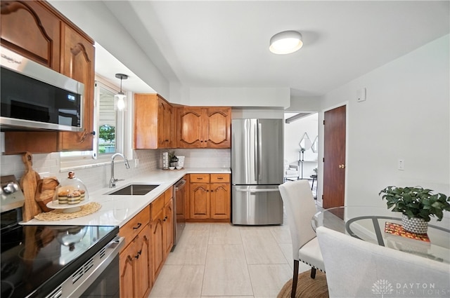 1023 Hilliard Dr, Delhi Twp, OH 45238 - kitchen with stainless steel appliances, brown cabinets, decorative backsplash, light countertops, and hanging light fixtures