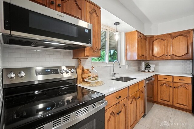 1023 Hilliard Dr, Delhi Twp, OH 45238 - kitchen with appliances with stainless steel finishes, brown cabinetry, tasteful backsplash, light countertops, and hanging light fixtures