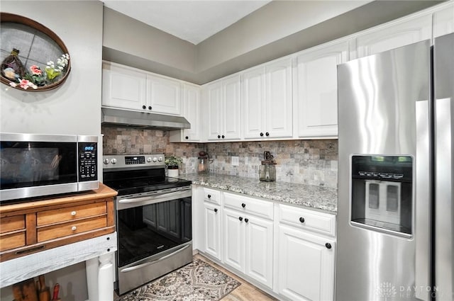 8425 Dillman Rd, Camden, OH 45311 - kitchen with appliances with stainless steel finishes, under cabinet range hood, white cabinetry, light stone counters, and tasteful backsplash