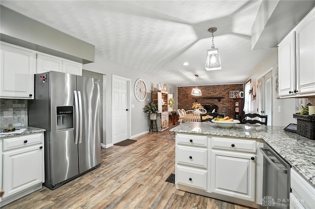 8425 Dillman Rd, Camden, OH 45311 - kitchen with stainless steel appliances, white cabinetry, hanging light fixtures, a peninsula, and brick wall