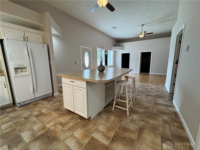 523 Newport Rd, Xenia, OH 45385 - kitchen with white fridge with ice dispenser, a ceiling fan, a textured ceiling, a kitchen island, and white cabinets