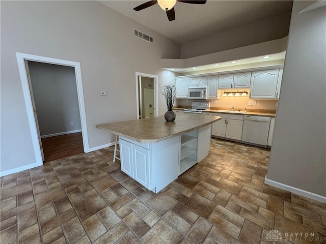 523 Newport Rd, Xenia, OH 45385 - kitchen featuring white appliances, stone tile flooring, a ceiling fan, white cabinets, and high vaulted ceiling