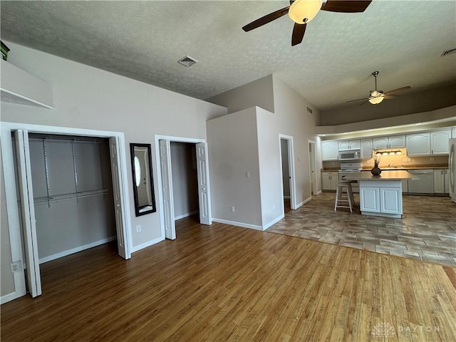 523 Newport Rd, Xenia, OH 45385 - unfurnished living room featuring a ceiling fan, a textured ceiling, light wood finished floors, and high vaulted ceiling