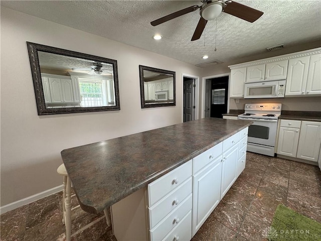 523 Newport Rd, Xenia, OH 45385 - kitchen featuring white appliances, dark countertops, white cabinets, a textured ceiling, and a kitchen island