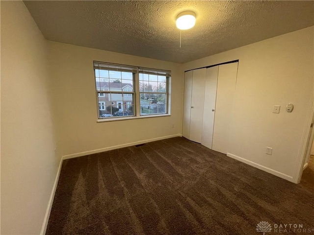 2133 Chapel Dr, Fairborn, OH 45324 - unfurnished bedroom featuring a textured ceiling, dark colored carpet, and a closet