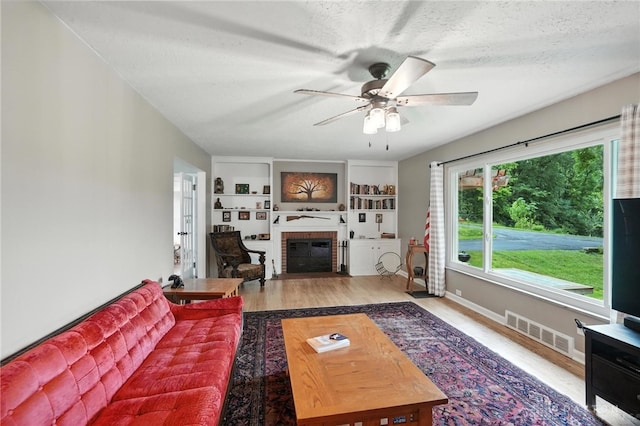 945 Oakland Dr, Beavercreek Twp, OH 45434 - living room with ceiling fan, wood finished floors, a fireplace, and a textured ceiling