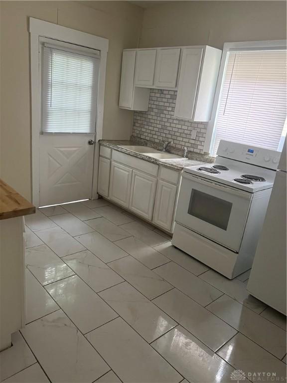208 Heaton Ave, Dayton, OH 45410 - kitchen featuring white range with electric cooktop, light marble finish floors, white cabinets, and backsplash