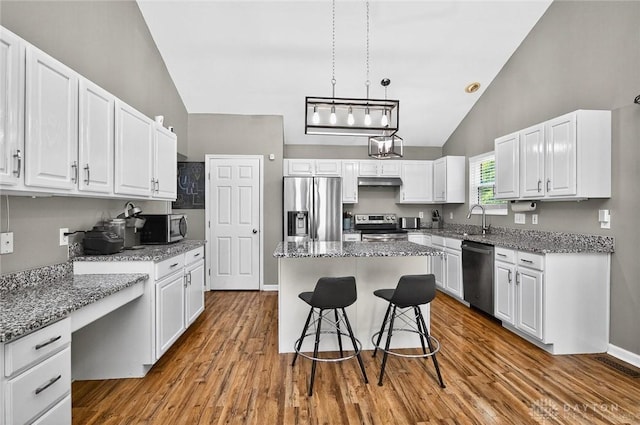2858 Willow Ridge Dr, Colerain Twp, OH 45251 - kitchen featuring stainless steel appliances, white cabinets, under cabinet range hood, wood finished floors, and high vaulted ceiling