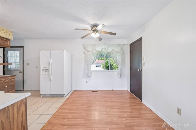 1513 Arrowhead Trl, Xenia, OH 45385 - kitchen with white refrigerator with ice dispenser, a ceiling fan, light tile patterned flooring, and light countertops