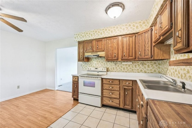 1513 Arrowhead Trl, Xenia, OH 45385 - kitchen featuring white range with electric stovetop, under cabinet range hood, ceiling fan, light countertops, and brown cabinetry